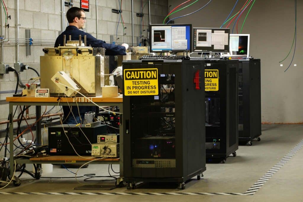 Technician monitoring real-time data across multiple continuous performance testing rigs and high-temperature furnaces for advanced material validation.