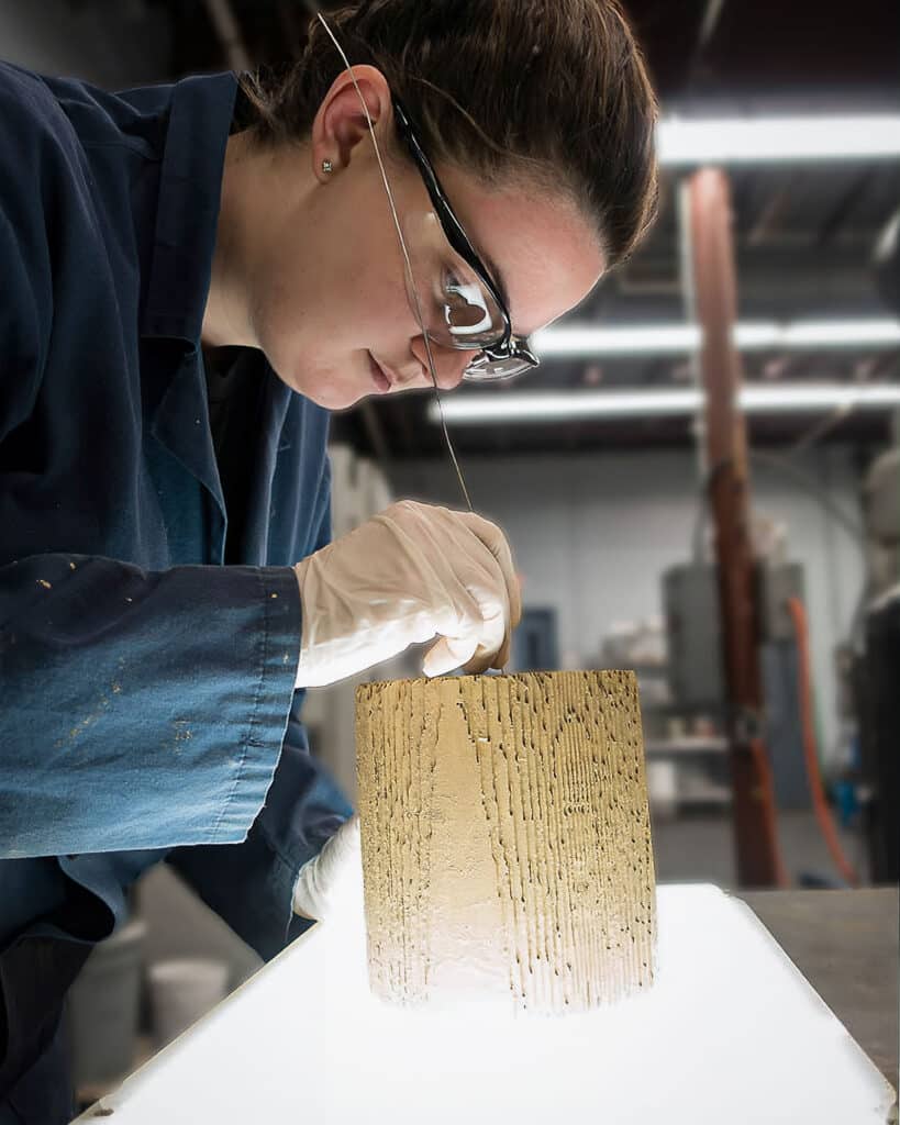 Technician performing a meticulous quality control inspection on a catalyst monolith using a light table.